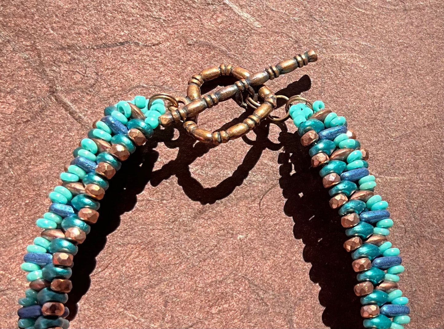 woven beaded bracelet in teals, copper and blue